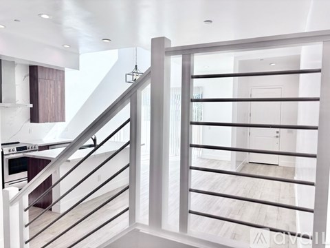 A modern interior with a staircase and a hanging light fixture.