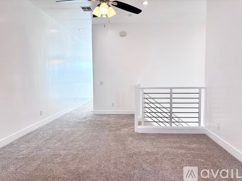 A room with a carpeted floor and a ceiling fan.