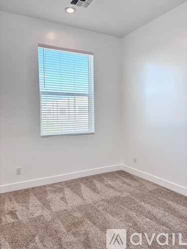 A room with a carpeted floor and a window with blinds.