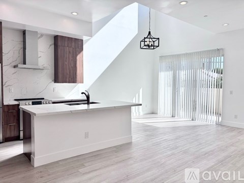 A modern kitchen with a white island and a stainless steel sink.