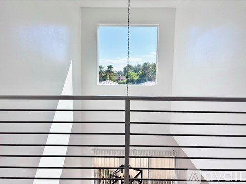 A balcony with a view of a street and trees.