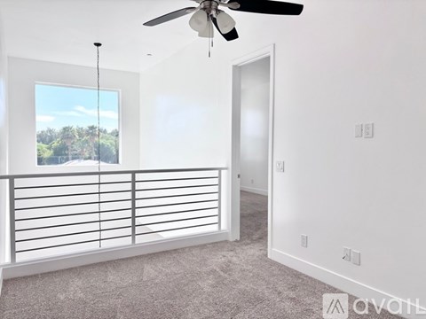 A room with a ceiling fan and a window overlooking a landscape.