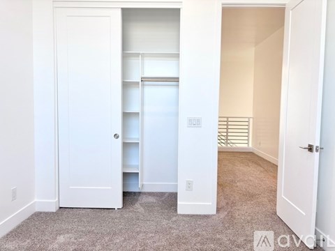 A white door is open to a hallway with a white wall.