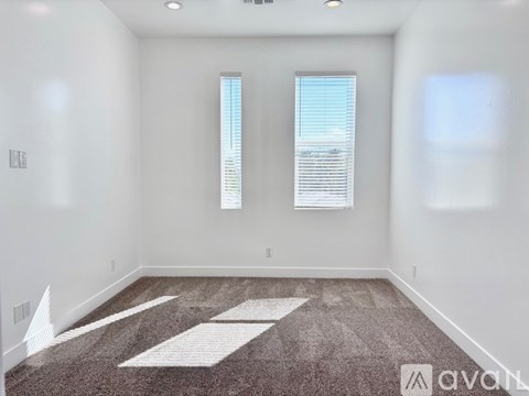 A room with a carpeted floor and two windows.