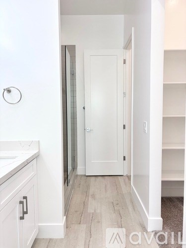 A white bathroom with a toilet, sink, and shelves.