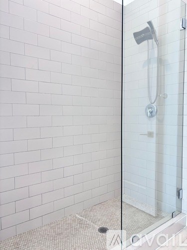 A white tiled shower with a glass door.