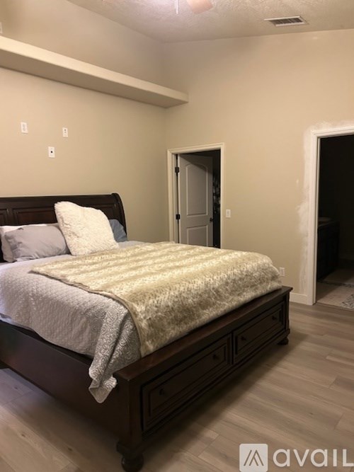 A bedroom with a bed, nightstands, and a doorway leading to another room.