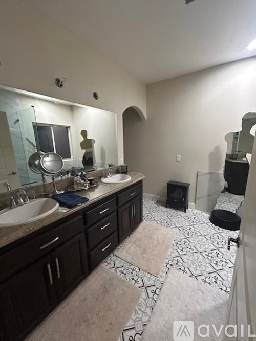 A bathroom with a large mirror, two sinks, and a tiled floor.