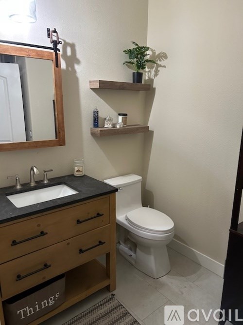 A bathroom with a toilet, sink, and shelves.