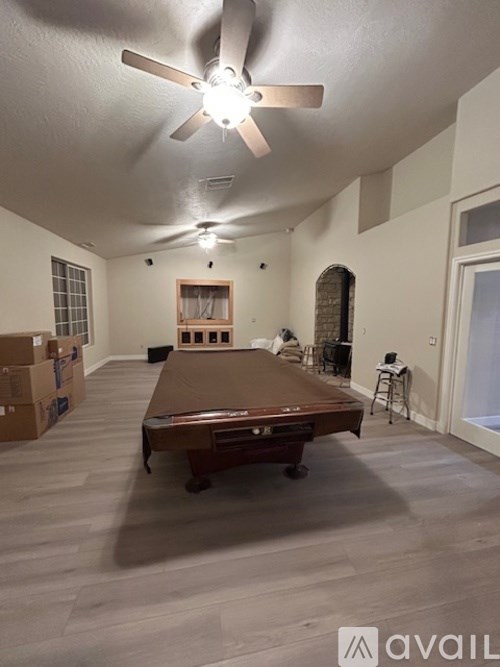 A room with a ceiling fan and a long table with chairs.