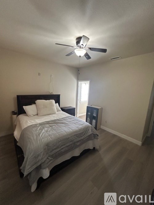 A bedroom with a bed, a ceiling fan, and a window.
