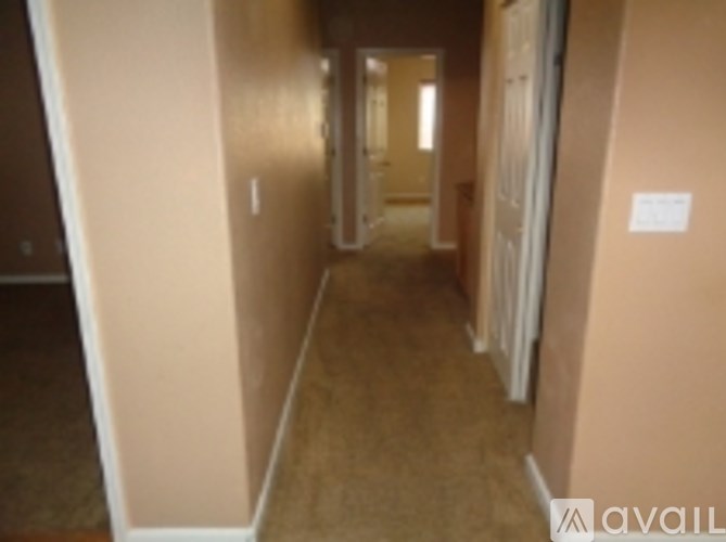 A hallway with a carpeted floor and beige walls.