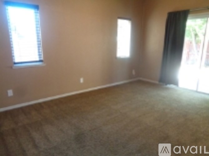 A room with a carpeted floor and two windows.
