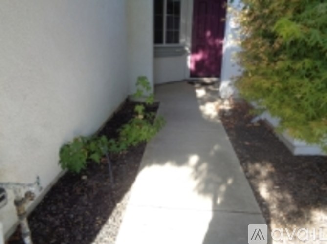 A white wall with a red door and a white walkway.