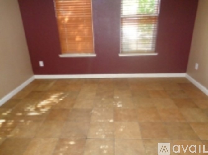 A room with wooden flooring and two windows.