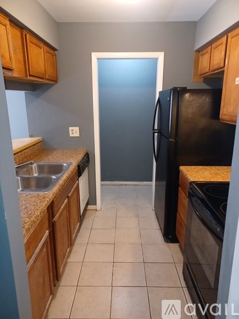 A kitchen with a black fridge and wooden cabinets.