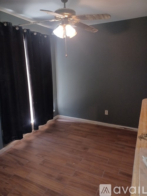 A room with a ceiling fan and wooden flooring.