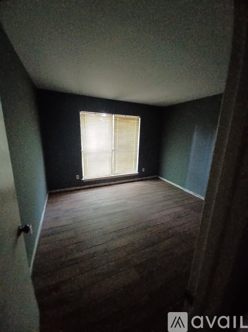 A room with wooden flooring and a window with blinds.