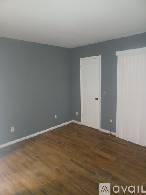 A room with a white door and a wooden floor.