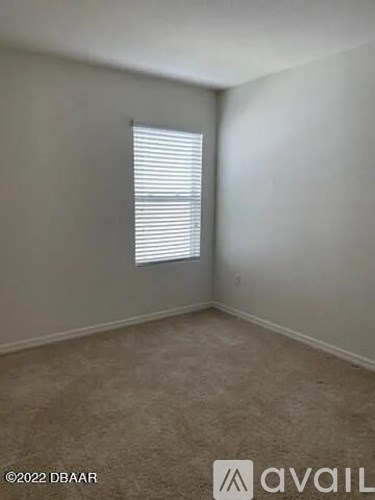 A room with a window covered by white blinds.
