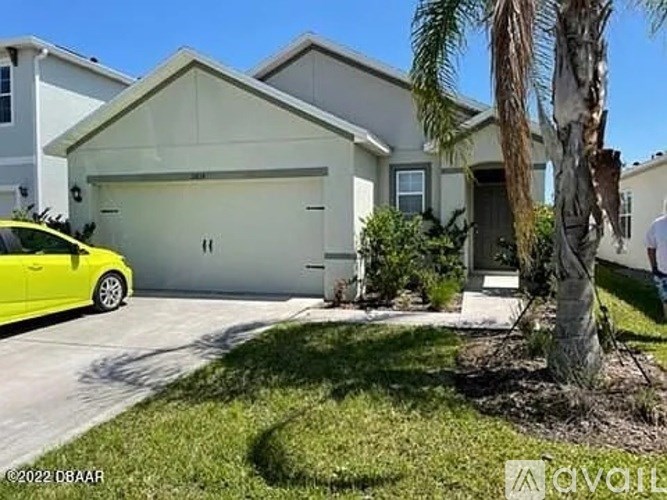 A yellow car is parked in front of a two-story house with a garage.