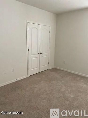 A room with a white door and carpeted floor.
