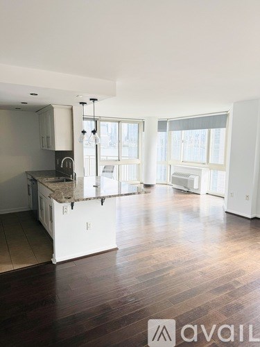 A large, empty kitchen with white cabinets and a wooden floor.