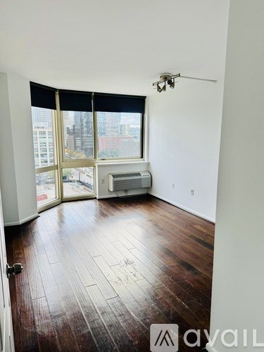 A room with wooden floors and a large window with blinds.