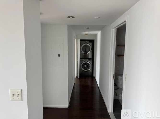 A long hallway with a washer and dryer in the doorway.