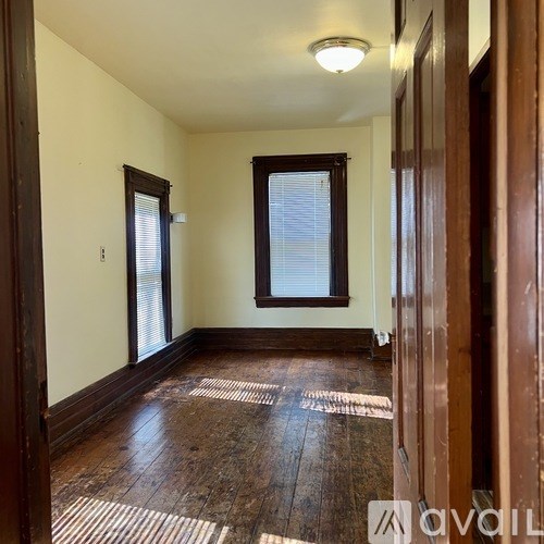 A room with wooden floors and a window with blinds.