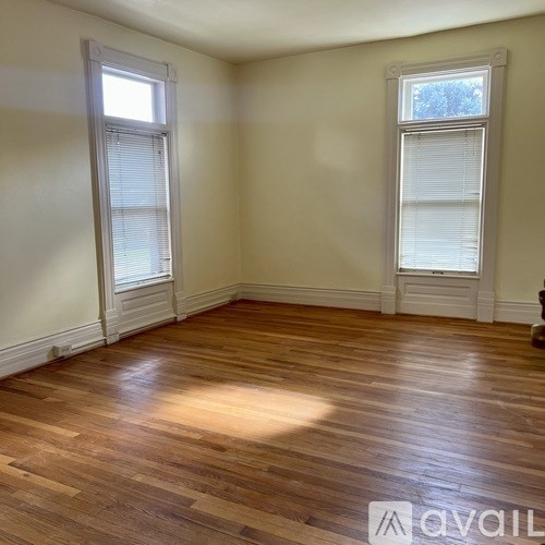 A room with wooden floors and two windows.