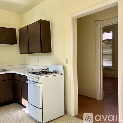 A white gas stove and oven in a kitchen with wooden cabinets.