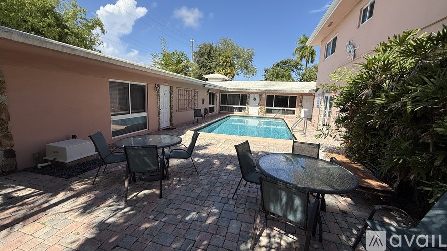 A patio with a table and chairs overlooking a pool.
