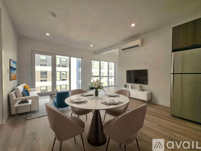 A spacious room with wooden flooring and large windows.