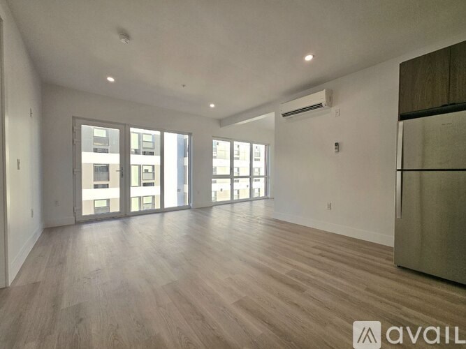 A spacious room with wooden flooring and large windows.