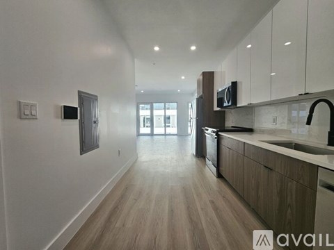 A modern kitchen with wooden floors and a large window.