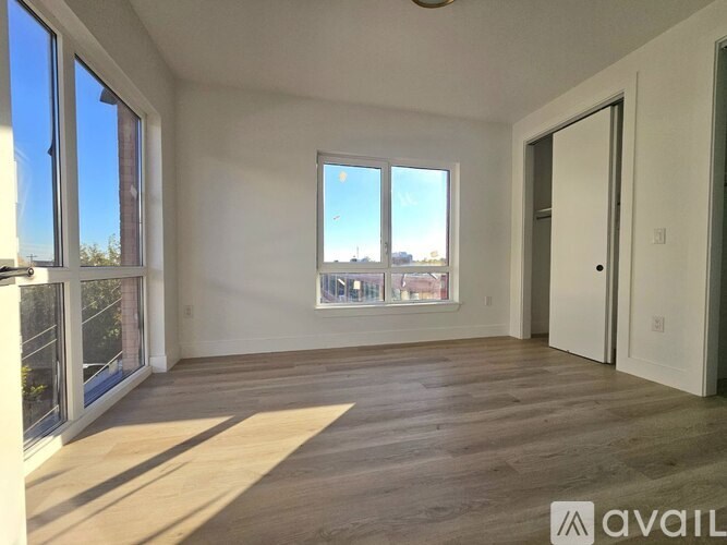 A spacious room with wooden flooring and large windows.