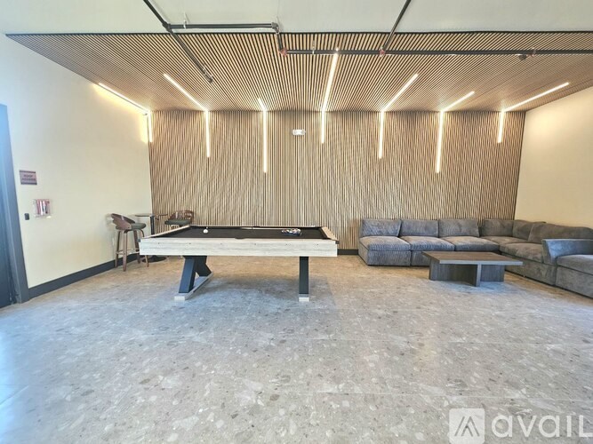A ping pong table is in the middle of a room with a couch and a chair.