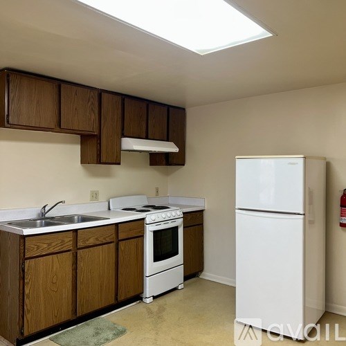 A kitchen with white appliances and wooden cabinets.