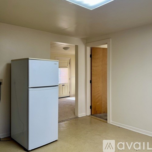A white refrigerator is in a room with a doorway leading to another room.