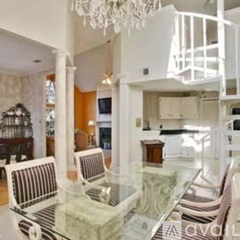 A living room with a glass table and striped chairs.