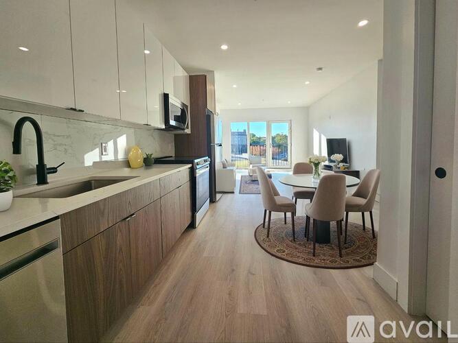 A modern kitchen with wooden floors and white cabinets.