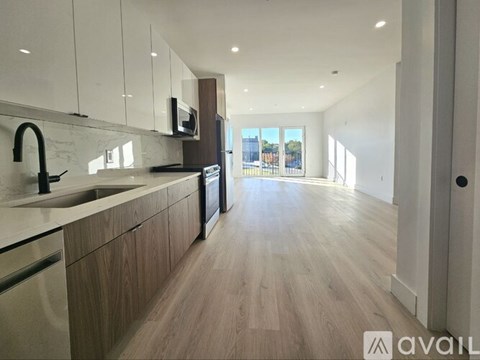 A modern kitchen with wooden floors and white cabinets.