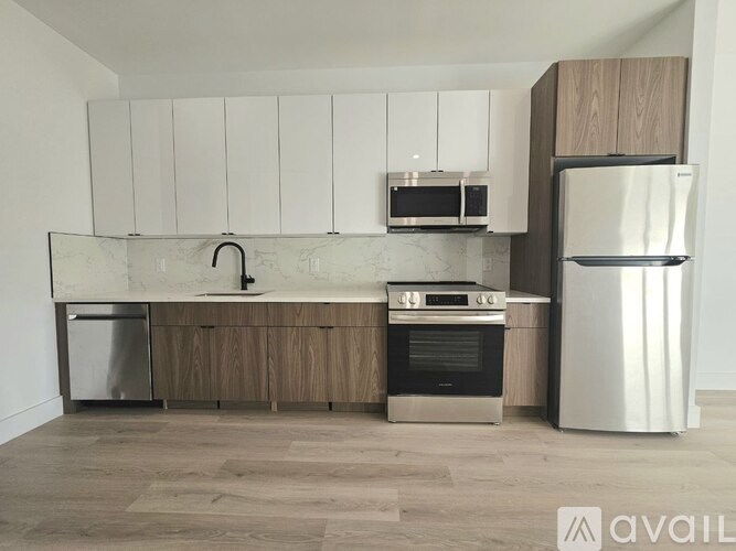 A modern kitchen with a refrigerator, oven, and microwave.