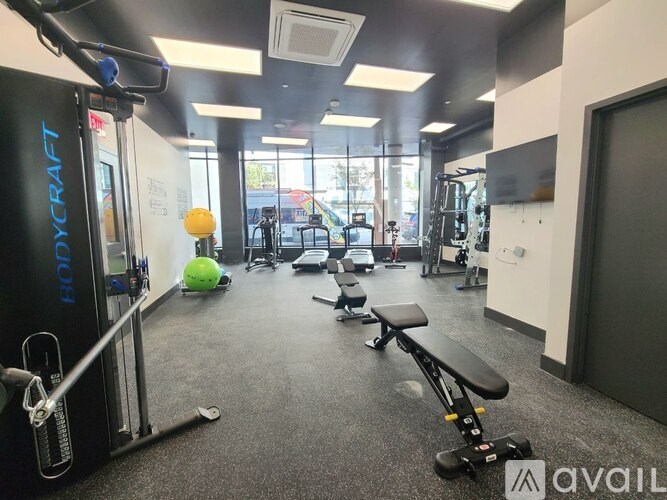 A gym with a variety of equipment including a squat rack, bench, and exercise balls.