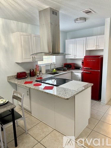 A kitchen with a red fridge and a marble island.
