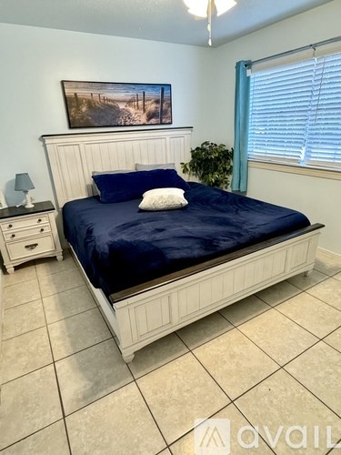 A bedroom with a bed, nightstand, and a painting on the wall.