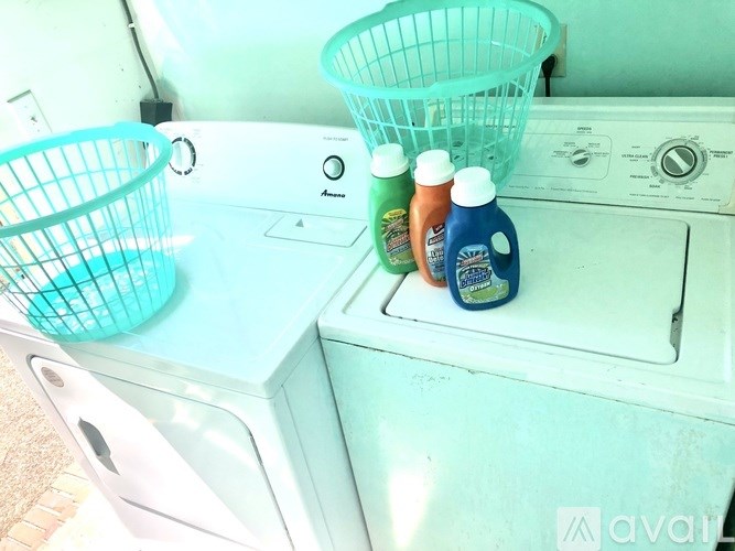A washing machine with a basket on top and two bottles of detergent on the door.