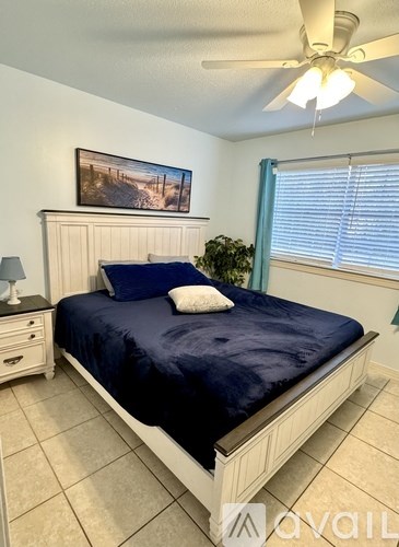 A bedroom with a bed, nightstand, and a painting on the wall.