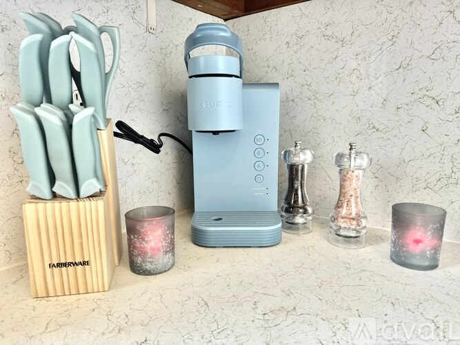 A blue lantern is on a table next to a set of knives and two candles.
